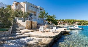 ein Haus auf dem Wasser mit Stühlen und einem Boot in der Unterkunft Seaside house for families with children Rogoznica - 22156 in Rogoznica