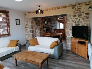 ein Wohnzimmer mit einem Sofa und einem TV in der Unterkunft Gîte Sainte-Suzanne-et-Chammes, 4 pièces, 6 personnes - FR-1-600-151 in Sainte-Suzanne
