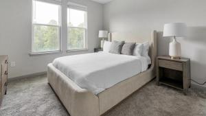 a white bedroom with a large bed and two windows at Landing Modern Apartment with Amazing Amenities (ID8935X21) in Middleburg