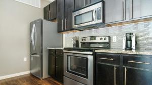 uma cozinha com electrodomésticos de aço inoxidável e armários pretos em Landing Modern Apartment with Amazing Amenities (ID5789X48) em El Paso