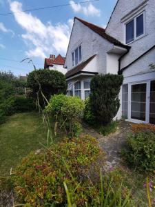 a white house with bushes in front of a yard at Double room minutes from the beach in Bexhill