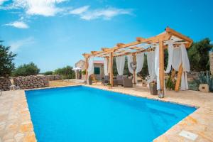 a swimming pool with a wooden pergola and a swimming poolvisor at Secluded house with a swimming pool Kosljun, Pag - 22238 in Pag