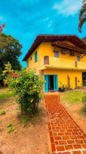 a yellow house with a brick path in front of it at Recanto das Estrelas in Marau