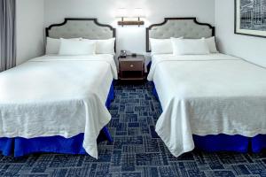 duas camas num quarto de hotel com lençóis brancos em Holland Hotel Free Parking Jersey City em Jersey City