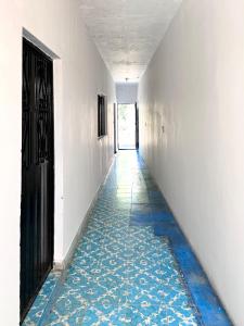 an empty hallway with a blue tile floor and a black door at Casa Huerta in Ciudad Fernández