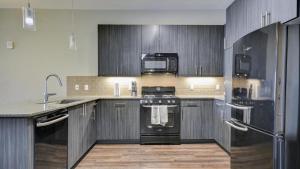 uma cozinha com armários pretos e um forno com placa de fogão em Landing Modern Apartment with Amazing Amenities (ID6644) em Sandy