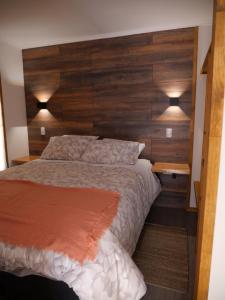 a bedroom with a bed with a wooden headboard at M House Pichilemu in Pichilemu