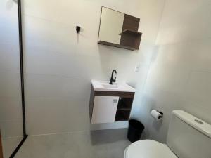 uma casa de banho com um WC, um lavatório e um espelho. em Temporada Praia Pinheira 2 Suítes 2 Garagens n2 em Palhoça
