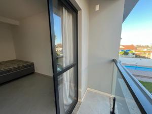 Habitación con ventana de cristal y balcón. en Temporada Praia Pinheira 2 Suítes 2 Garagens n2 en Palhoça