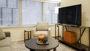 uma sala de estar com uma televisão, uma cadeira e uma mesa em Landing Modern Apartment with Amazing Amenities (ID8398X48) em Omaha