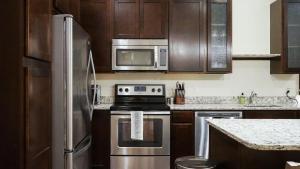 kuchnia z urządzeniami ze stali nierdzewnej i drewnianymi szafkami w obiekcie Landing Modern Apartment with Amazing Amenities (ID8398X48) w mieście Omaha