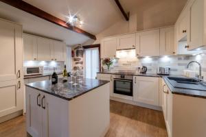 cocina con armarios blancos y encimera en Bridge End Farm Cottages en Boot