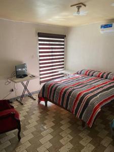 1 dormitorio con cama, escritorio y ventana en Paulora, en Hidalgo del Parral