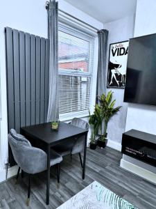 uma sala de estar com uma mesa preta e uma televisão em Large 4 Bedroom TownHouse with Free Parking Near MCR Center em Manchester