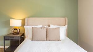 - un lit avec des oreillers blancs et une lampe sur une table dans l'établissement Landing Modern Apartment with Amazing Amenities (ID1193X713), à Indianapolis