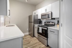 a kitchen with stainless steel appliances and white cabinets at Landing Modern Apartment with Amazing Amenities (ID8723X6) in Phoenix