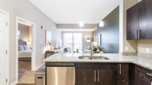 uma cozinha com um lavatório e um quarto com uma cama em Landing Modern Apartment with Amazing Amenities (ID7010X69) em Fort Wayne