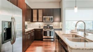 Landing Modern Apartment with Amazing Amenities (ID5143X81) في ذا وودلاندس: مطبخ مع أجهزة ستانلس ستيل ودواليب خشبية