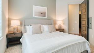 una camera da letto con un grande letto bianco con due lampade di Landing Modern Apartment with Amazing Amenities (ID5143X81) a The Woodlands
