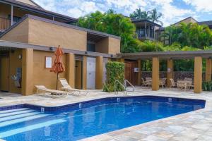 a pool with chairs and an umbrella next to a house at Wailea Elua #202 — Huge Views — Luxury Remodel in Wailea