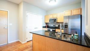 Landing Modern Apartment with Amazing Amenities (ID7380X13) في سانت بول: مطبخ مع ثلاجة ستيل ستانلس ودواليب خشبية