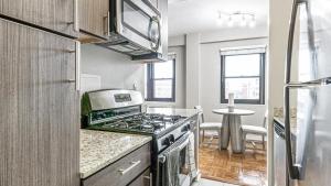 a kitchen with a stove top oven next to a table at Landing Modern Apartment with Amazing Amenities (ID9104X34) in Alexandria