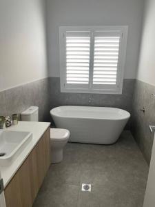 een badkamer met een bad, een toilet en een wastafel bij Hamptons House Mudgee -Lux Stays in Mudgee