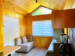 a kitchen with a couch and a window in a room at Cabañas Kalinaw in Las Trancas