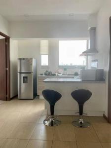 una cucina con 2 sgabelli da bar e un frigorifero di La mejor opción Departamento Senza 3 a El Gallinero