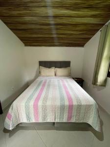 a bed with a striped comforter in a room at Pousada Recanto Verde in Sana