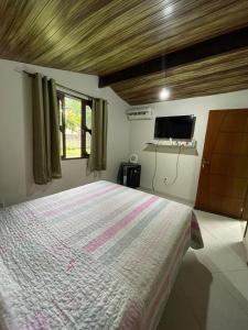 a bedroom with a large bed and a television at Pousada Recanto Verde in Sana