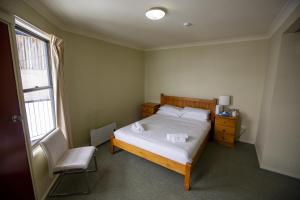 a bedroom with a bed and a chair and a window at Lucy Lodge in Charlotte Pass