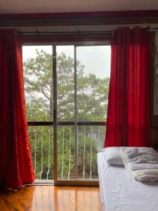 a bedroom with a large window with red curtains at Casa Valle Verde in Baguio