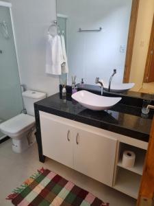 La salle de bains est pourvue d'un lavabo et de toilettes. dans l'établissement Villa do Aconchego apartamento super novo, à Búzios