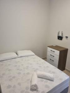 a bed with two towels on it next to a dresser at Villa do Aconchego apartamento super novo in Búzios