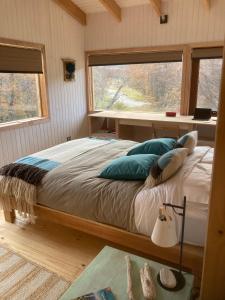 - une chambre avec un lit doté d'oreillers et d'une fenêtre dans l'établissement Acogedora casa en bosque Cerro Castillo cercana Parque, à Villa Cerro Castillo