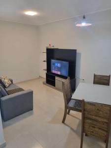 uma sala de estar com uma televisão, uma mesa e um sofá em Villa do Aconchego apartamento super novo em Búzios