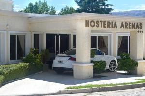 un coche blanco estacionado frente a un edificio en Hosteria Arenas en Mina Clavero