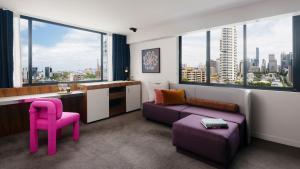 シドニーにあるラーモント シドニー バイ ランスモアのリビングルーム(紫色のソファ、ピンクの椅子付)