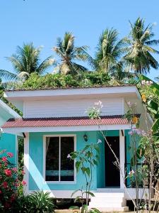 ヤオノイ島にあるํYada Resort Koh Yao Noiのヤシの木が茂る緑の屋根の家