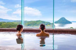 dos chicas sentadas en una piscina mirando hacia el agua en Ooedo Onsen Monogatari Amakusa Hotel Kameya, en Kami Amakusa