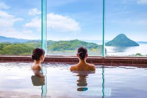 two girls sitting in a swimming pool looking out at the water at Ooedo Onsen Monogatari Amakusa Hotel Kameya in Kami Amakusa +20 photos