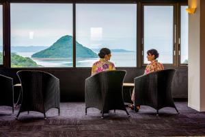 Deux femmes assises à une table qui regarde par la fenêtre dans l'établissement Ooedo Onsen Monogatari Amakusa Hotel Kameya, à Kami Amakusa