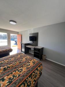 ein Hotelzimmer mit einem Bett und einem Flachbild-TV in der Unterkunft Pioneer INN in Arkadelphia