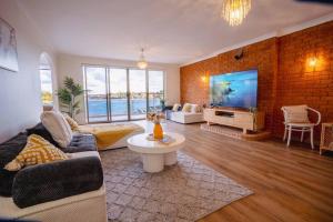 シドニーにあるStunning waterfront townhouse with shared swimpool, harbour view and free Pのソファとテレビのあるリビングルーム