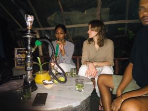 dos mujeres sentadas alrededor de una mesa con una bebida en Dinna Nature Hostel, en Sigiriya