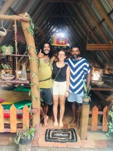 un grupo de tres personas parados frente a una casa en Dinna Nature Hostel, en Sigiriya