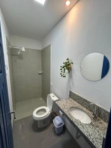 La salle de bains est pourvue de toilettes, d'un lavabo et d'un miroir. dans l'établissement Casa Grécia Pousada, à Santo Amaro