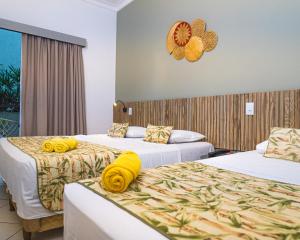 Dos camas en una habitación de hotel con toallas amarillas. en Hotel Ilhas do Caribe - Na melhor região da Praia da Enseada, en Guarujá