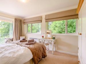a bedroom with a bed and a desk and windows at 3 bed property in Godshill New Forest 56431 in Godshill